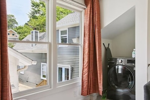 A laundry room with a window, a washing machine, and a view of neighboring houses. - Chic ATL Stay | Private, Near BeltLine + Parking (Atlanta)