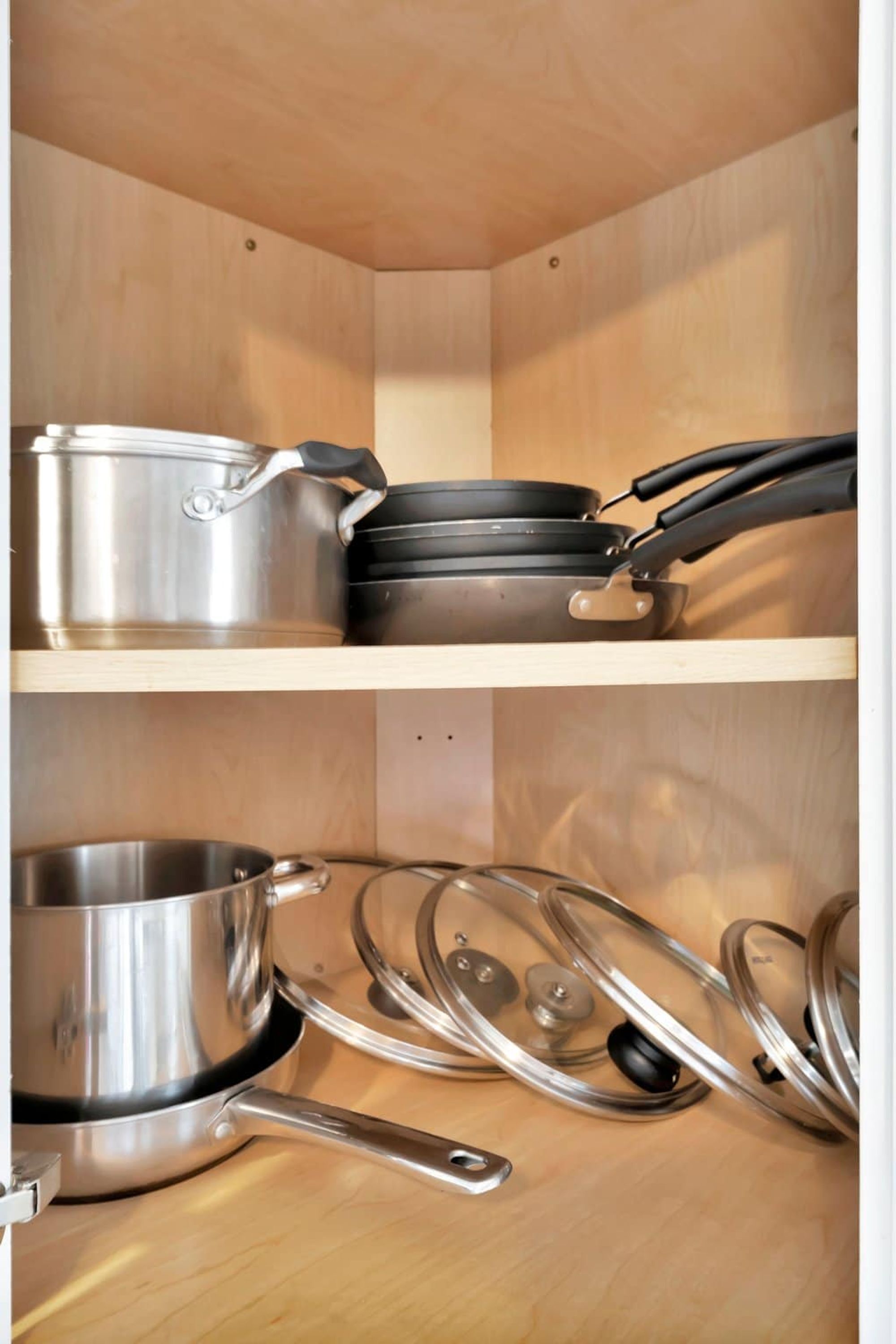 Une cuisine avec des casseroles et des poêles en acier inoxydable, rangées sur des étagères en bois.