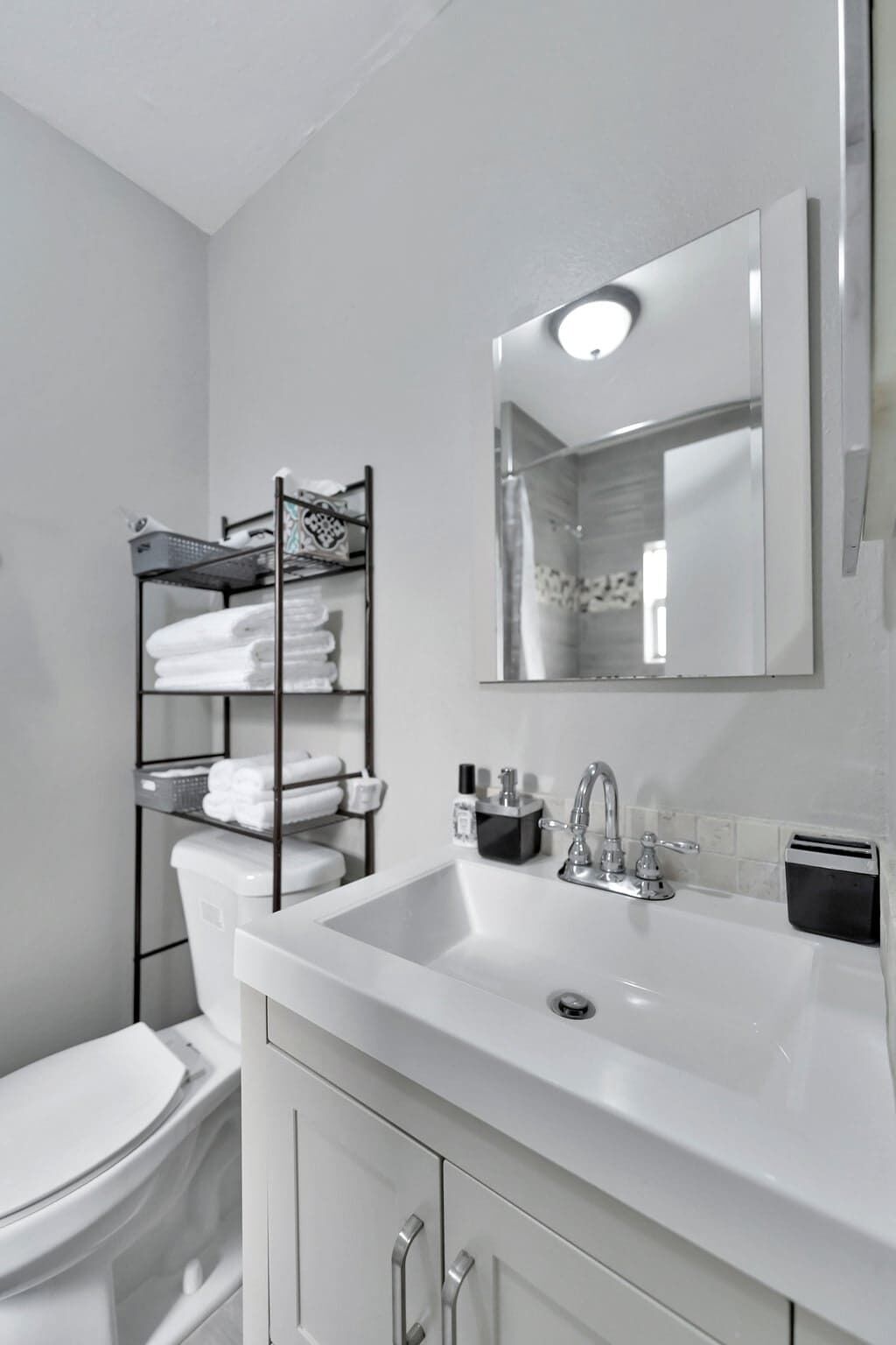 A bathroom with a white sink, a mirror, a towel rack, and a toilet.