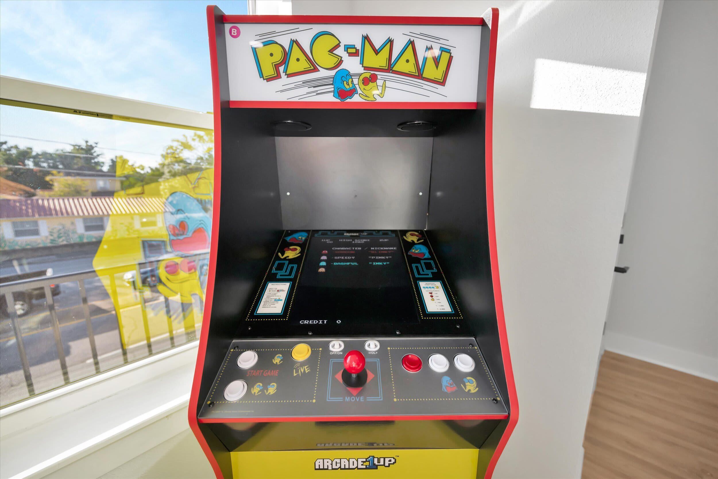 A Pac-Man arcade machine with a yellow base and red accents, featuring a joystick and buttons labeled "START GAME," "LIVE," "MOVE," and "CREDIT."