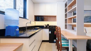A modern kitchen with a built-in island, a water dispenser, a coffee maker, and a dishwasher. - Studio 290 m From Praia Mole Vds0005 (Florianópolis)