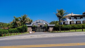 A gated entrance with a modern archway, surrounded by palm trees and a well-maintained lawn. - Studio 290 m From Praia Mole Vds0005 (Florianópolis)
