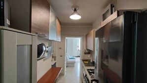 Una cucina piccola con lavatrice, fornello e frigorifero.