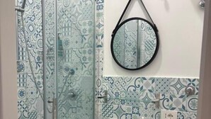 A bathroom with patterned tiles, a glass shower enclosure, a sink, a toilet, and a mirror. - B&B Napoli Tonic (Naples)