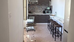 A narrow hallway leading to a kitchen with a dining area, a ceiling light, and tiled flooring. - B&B Napoli Tonic (Naples)