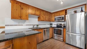 Una cocina moderna con armarios de madera, electrodomésticos de acero inoxidable y encimera de granito.