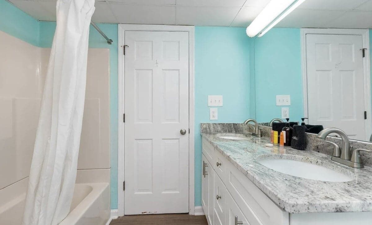 Une salle de bain avec deux lavabos, une douche et une porte.