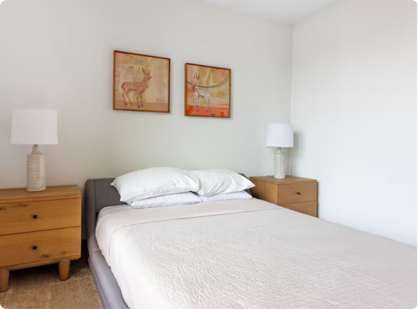 A bedroom with a bed, two nightstands, and two wall-mounted lamps.