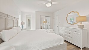 Ein Schlafzimmer mit einem großen Bett, einem Deckenventilator, einer Kommode und einem Spiegel.