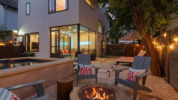Ein Garten mit Feuerstelle, Liegestühlen und Schwimmbad.