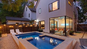Ein modernes Haus mit Swimmingpool, Sitzgelegenheit im Freien und einem Wintergarten-Essbereich.