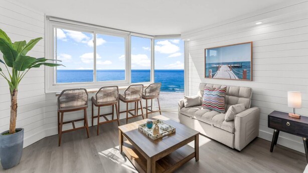 A room with a view of the ocean, featuring a sofa, chairs, a coffee table, and a painting. - Renovated Beach Front Ocean View Condo TOG 723 (Panama City Beach)