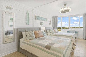 A bedroom with two beds, a large window, and a view of the beach. - Beach Front Ocean View Condo - Top of the Gulf 804 (Panama City Beach)