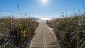 A pathway leading to the beach with the sun shining brightly in the sky. - Top of the Gulf 620 Beachfront Couples Retreat (Panama City Beach)