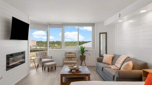 A modern living room with a fireplace, a sofa, a coffee table, and a TV mounted on the wall. - Top of the Gulf 622 - Beach Front Condo Resort (Panama City Beach)