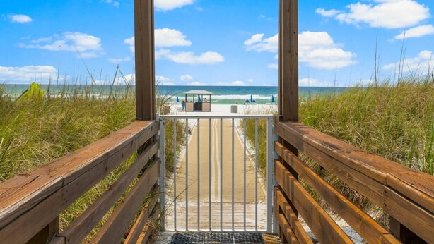A wooden boardwalk leading to a beach with a gazebo and lounge chairs. - Top of the Gulf 622 - Beach Front Condo Resort (Panama City Beach)