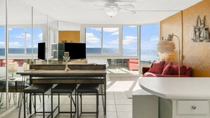 A modern kitchen with a large island, bar stools, and a view of the ocean. - Top of the Gulf 421 - Luxury Beach View Condo (Panama City Beach)