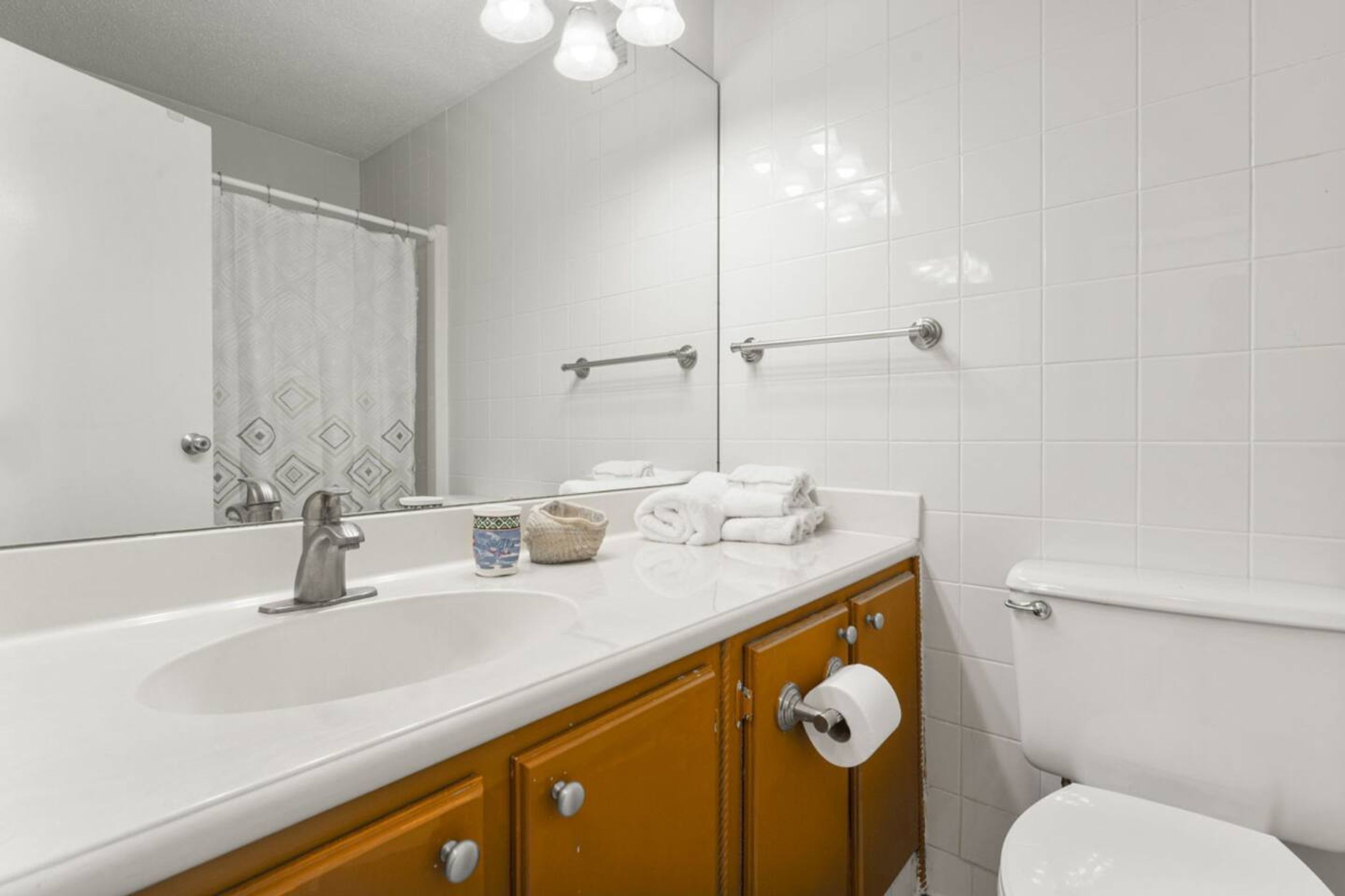 Een badkamer met een wit wastafel, een spiegel, een handdoekhouder en een toilet.