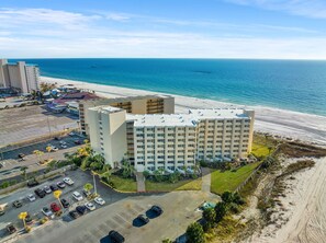 Ein Strandhotel mit mehreren Etagen, einem Parkplatz und Blick auf den Ozean.