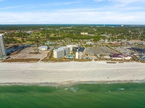 Eine Luftaufnahme eines Küstenresorts mit mehreren Gebäuden, darunter ein Hotel mit Pool und Zugang zum Strand.