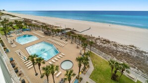 A resort with two swimming pools, a beach, and a fenced area with lounge chairs. - Summit 808 - Luxury Beach Resort Condo 1-6 People (Panama City Beach)