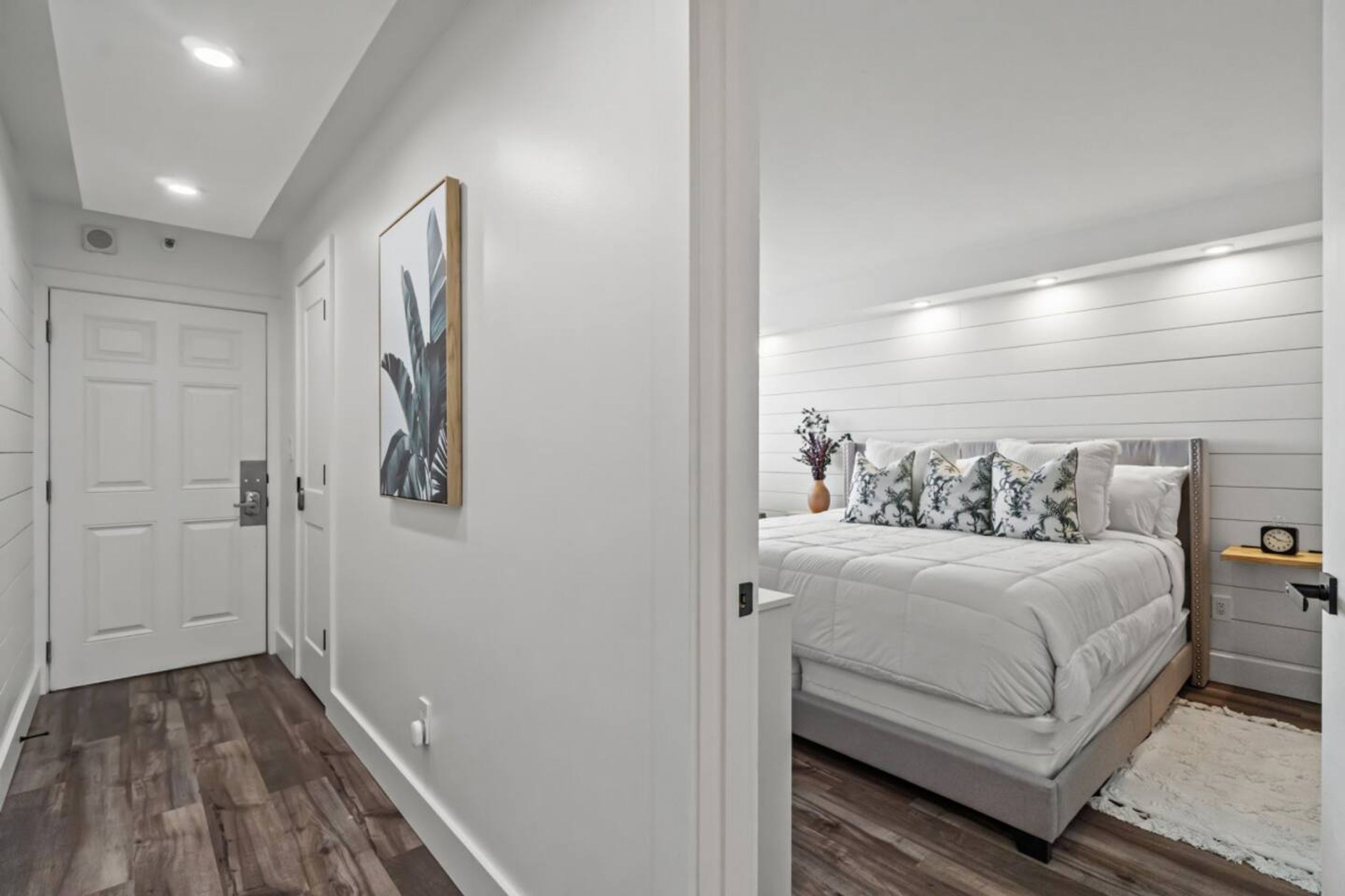 A bedroom with a bed, a nightstand, and a wall-mounted shelf.