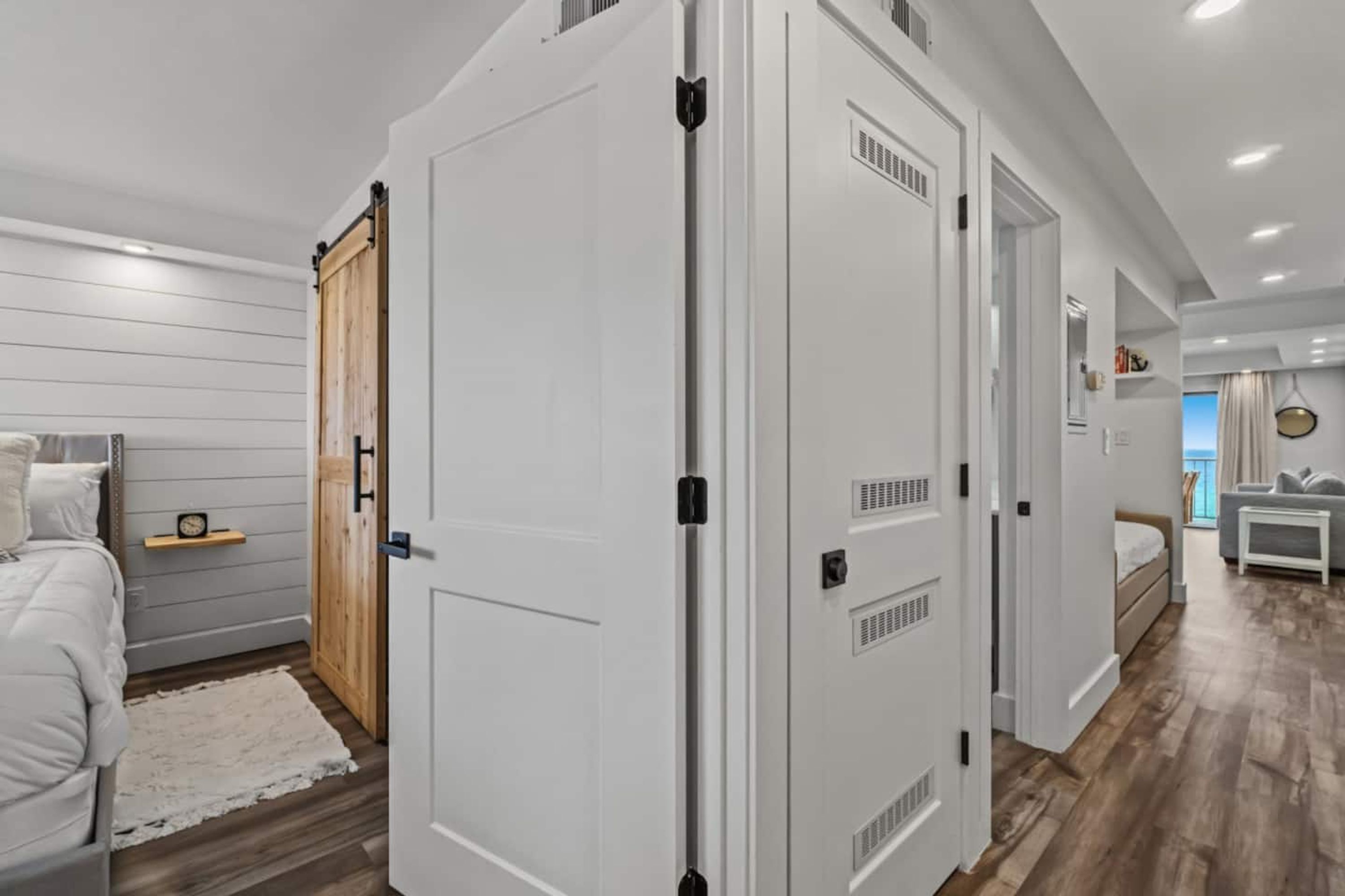 A bedroom with a bed, a wooden wardrobe, and a white door.