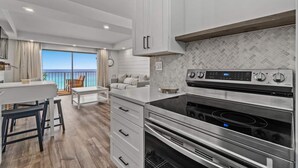 A modern kitchen with a large oven, white cabinetry, and a view of the ocean.