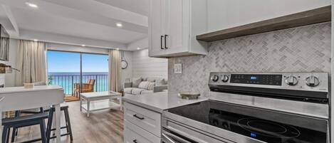 A modern kitchen with white cabinets, a black stove, and a herringbone-patterned backsplash.