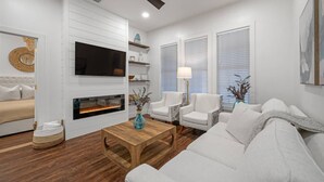 A modern living room with a fireplace, white sofas, a coffee table, and a TV mounted on the wall.