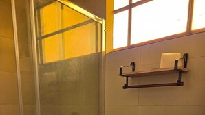 Un baño con cabina de ducha de vidrio, inodoro y lavamanos.