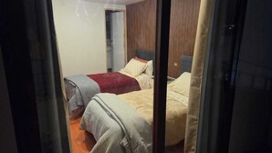 Un dormitorio con dos camas, paneles de madera y la puerta del baño a la vista.
