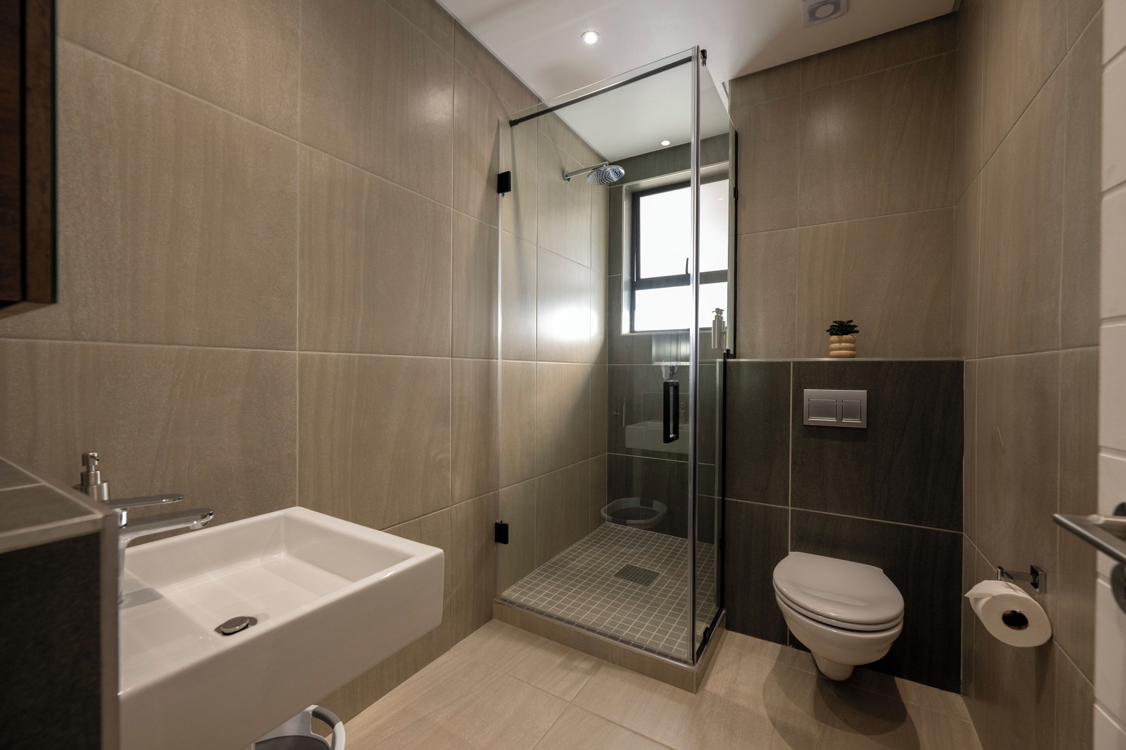 Une salle de bain moderne avec une douche à parois de verre, un lavabo blanc et des toilettes.