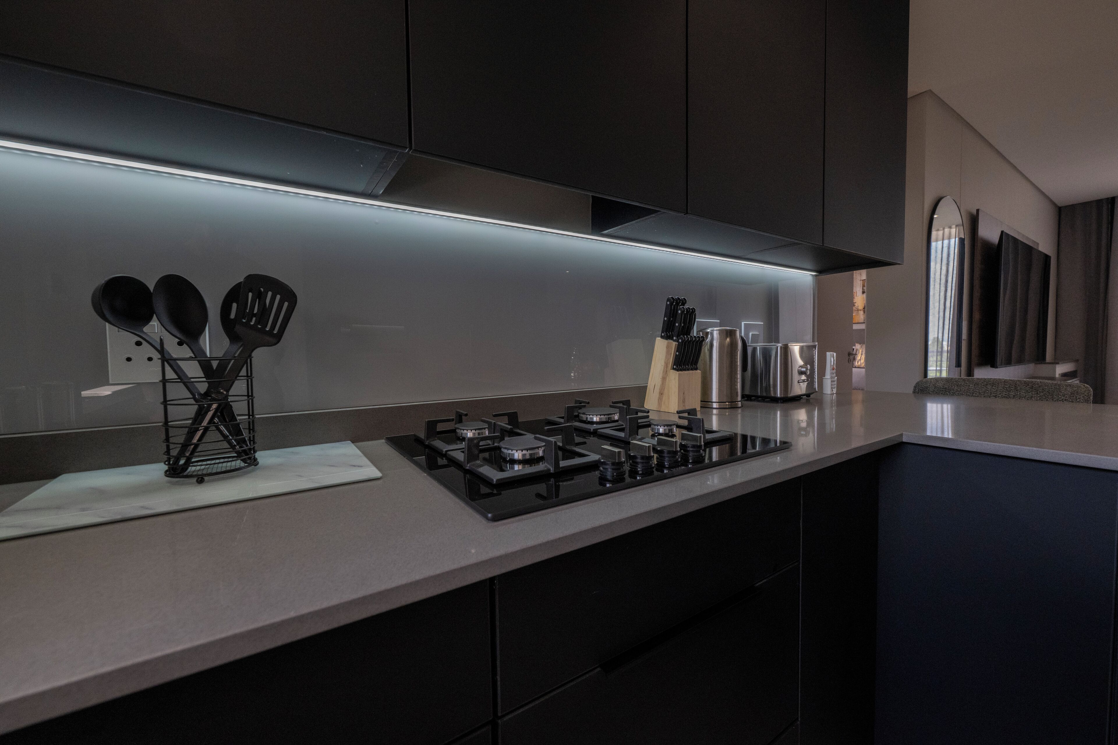 Een moderne keuken met een gasfornuis, roestvrijstalen apparatuur en zwarte kasten.