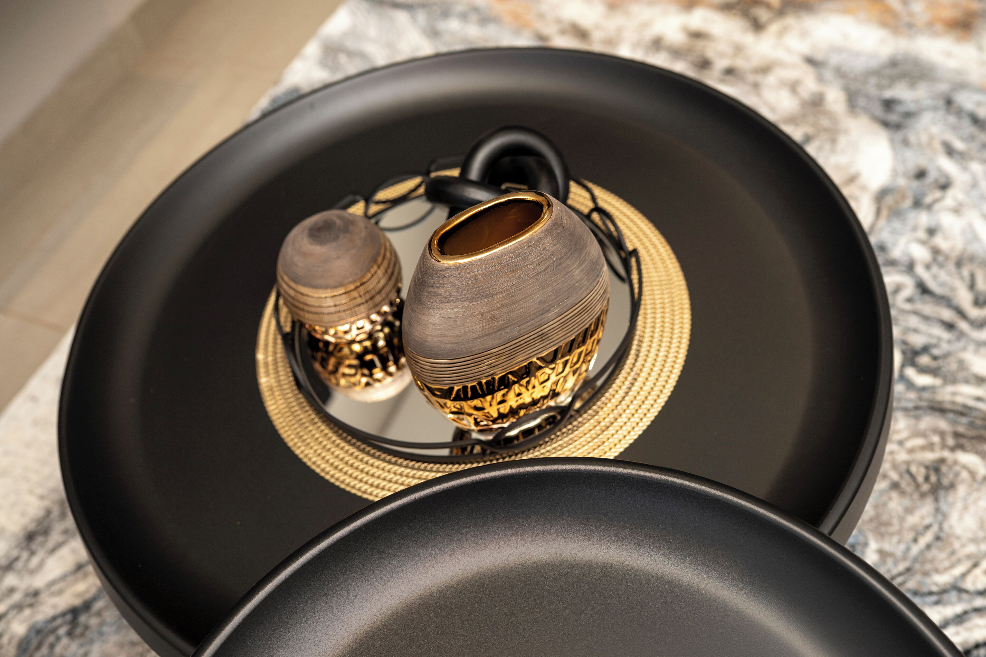 A black tray with two decorative vases on a marble surface.