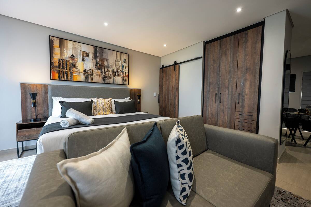 Un dormitorio moderno con una cama grande, un sofá y un armario.