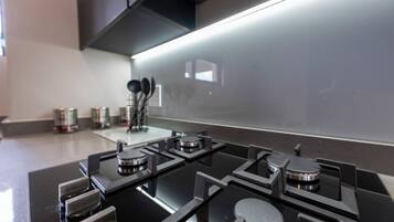 A modern kitchen with a black stove top, stainless steel handles, and a backsplash.