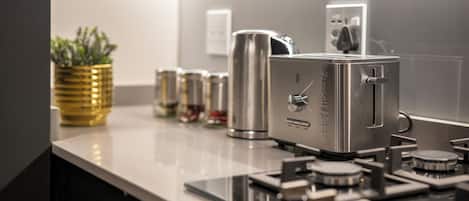 A modern kitchen with stainless steel appliances, a coffee machine, and a kettle.