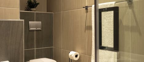 Un baño moderno con inodoro, lavamanos y cabina de ducha de vidrio.