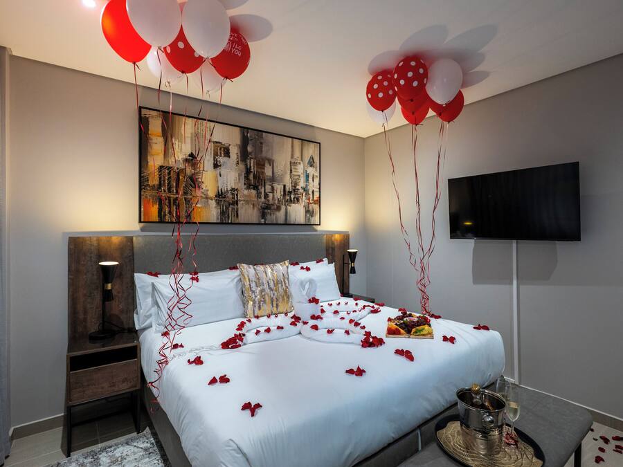 A hotel room with a bed, a TV, and a painting on the wall.