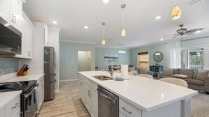 A modern kitchen with stainless steel appliances, a large island, and pendant lighting. - Introducing The Barefoot Villa in Lost Key! For An Upscale-Coastal Vacation. (Pensacola)