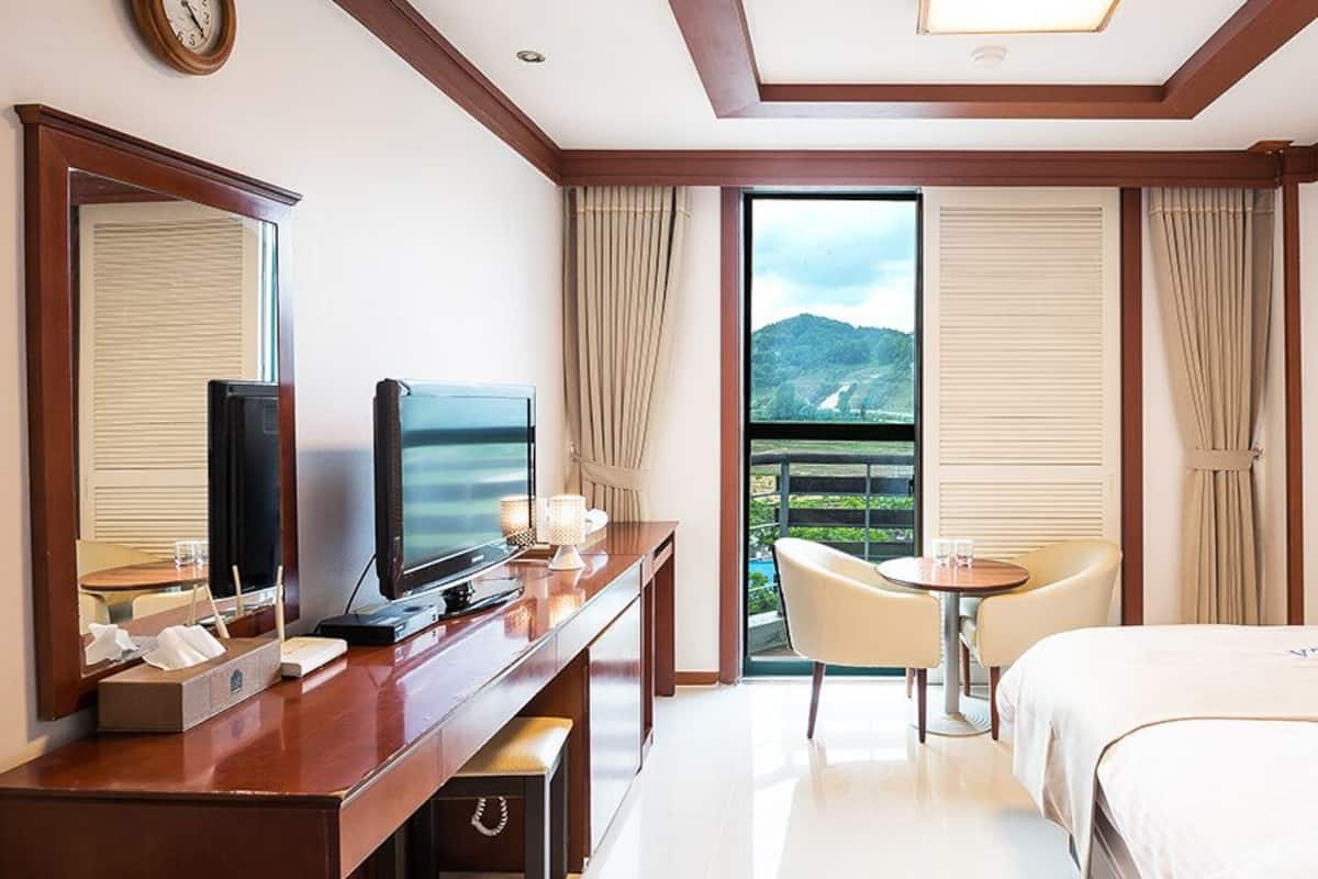 Ein Hotelzimmer mit Bett, Schreibtisch mit Fernseher, Stuhl und Bergblick durch das Fenster.