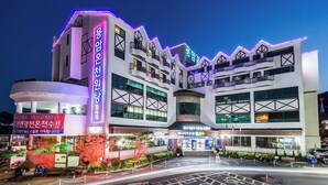 A modern building with multiple floors and balconies, featuring illuminated signage and a well-lit entrance area. - Benikea Hotel CheongDo Hot Spring (Cheongdo)