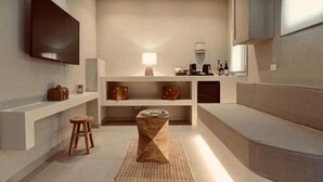 A modern, minimalist bathroom with a flat-screen TV, a wooden stool, and a built-in bench. - Exclusive Rooms at Boutique Arte   (Palermo)