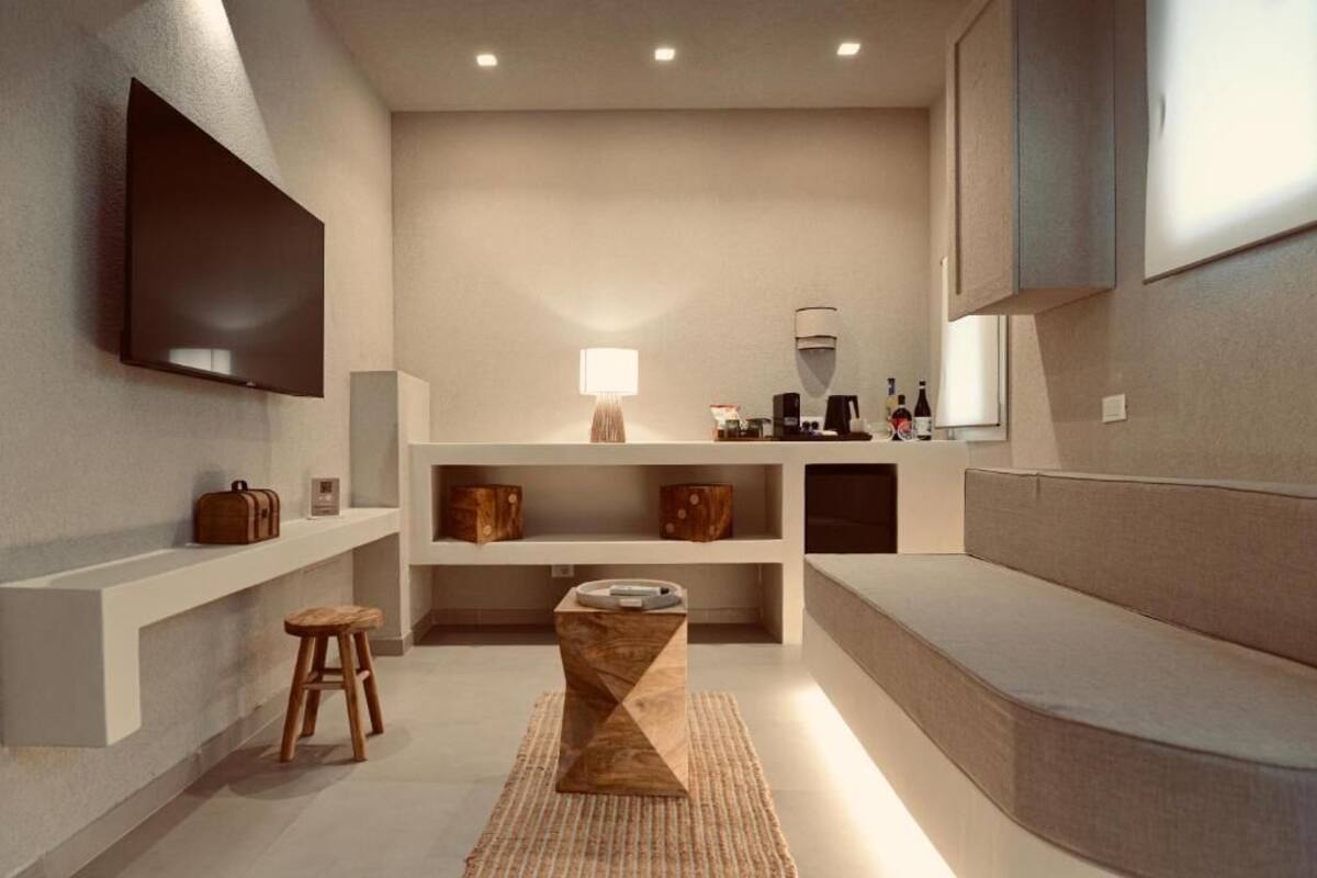 Un baño moderno y minimalista con una televisión de pantalla plana, un taburete de madera y un banco empotrado.