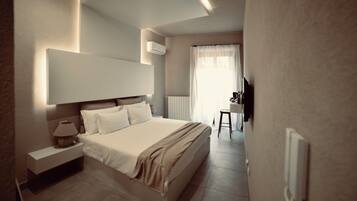 Una habitación de hotel moderna con una cama grande, mesita de noche, lámpara y vistas al baño.