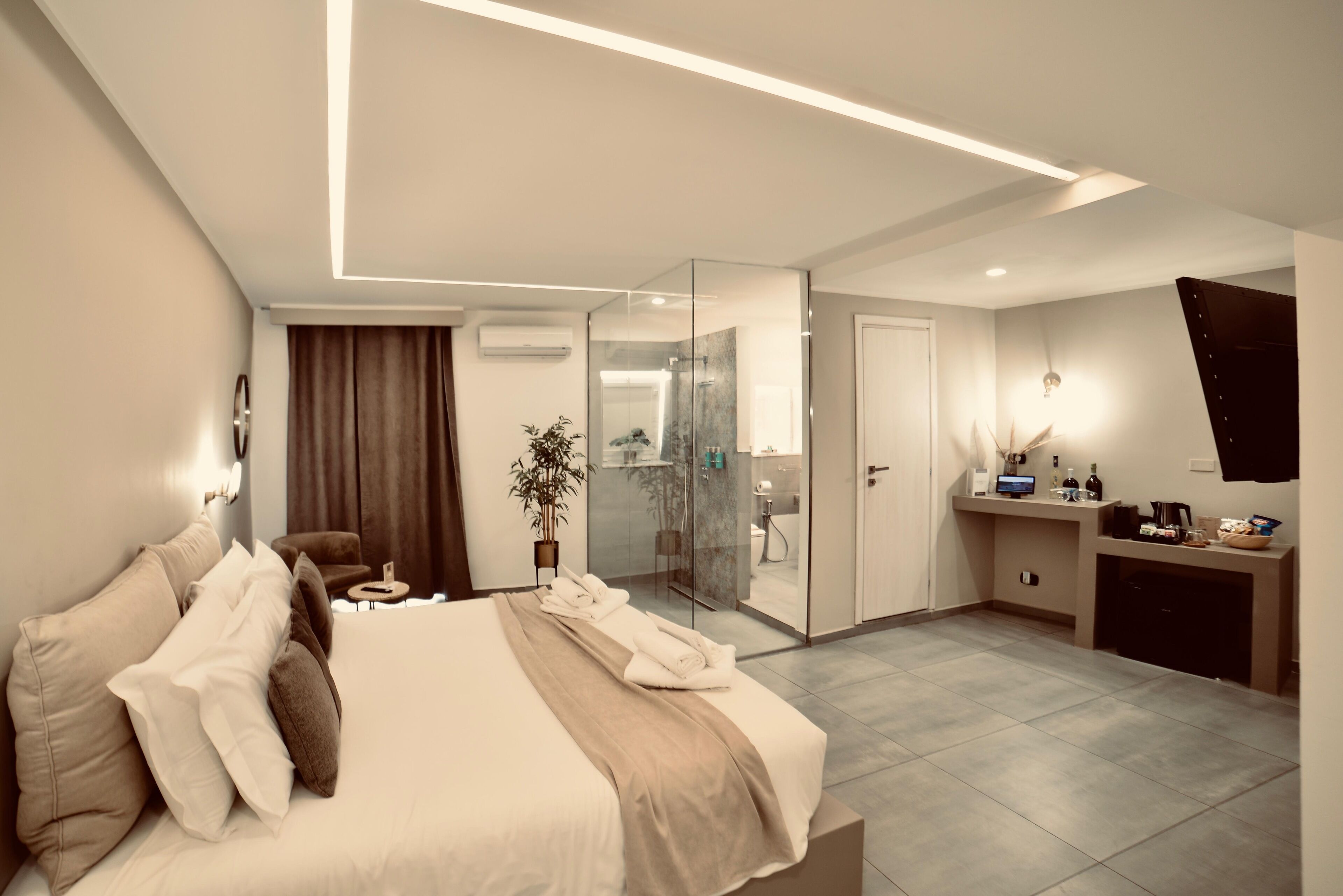 A modern hotel room with a large bed, a desk, and a glass shower area.