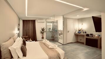 A modern hotel room with a large bed, a desk, and a glass shower area.