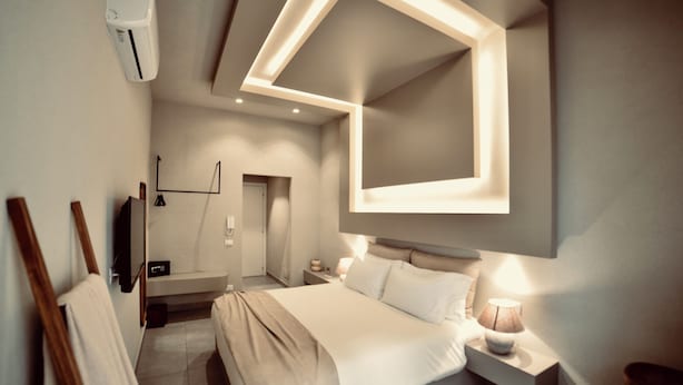 A modern bedroom with a large bed, bedside tables, a wall-mounted TV, and a ceiling light fixture. - Exclusive Rooms at Boutique Arte   (Palermo)