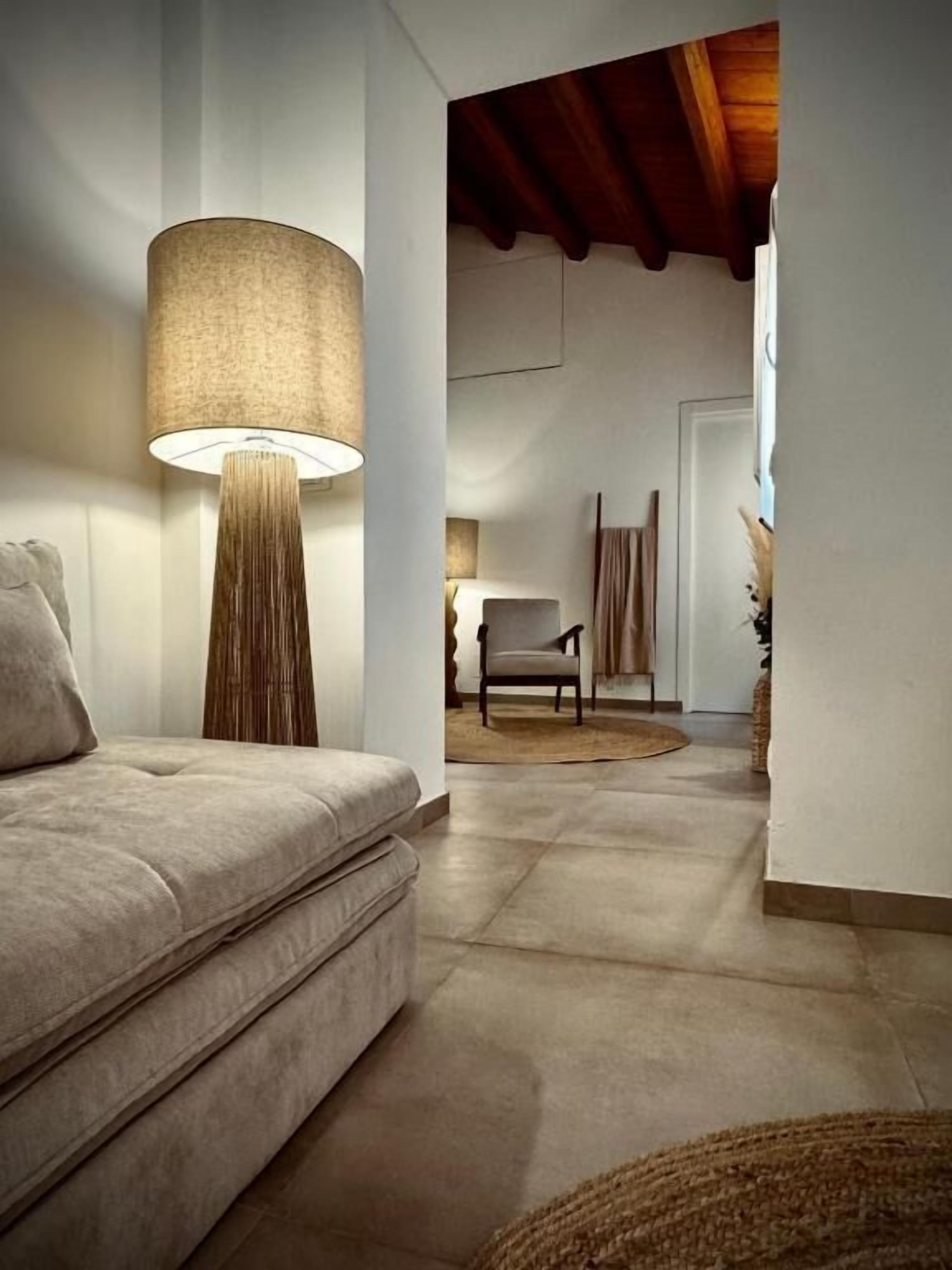 Uma sala de estar moderna com um sofá, um abajur alto e uma poltrona.